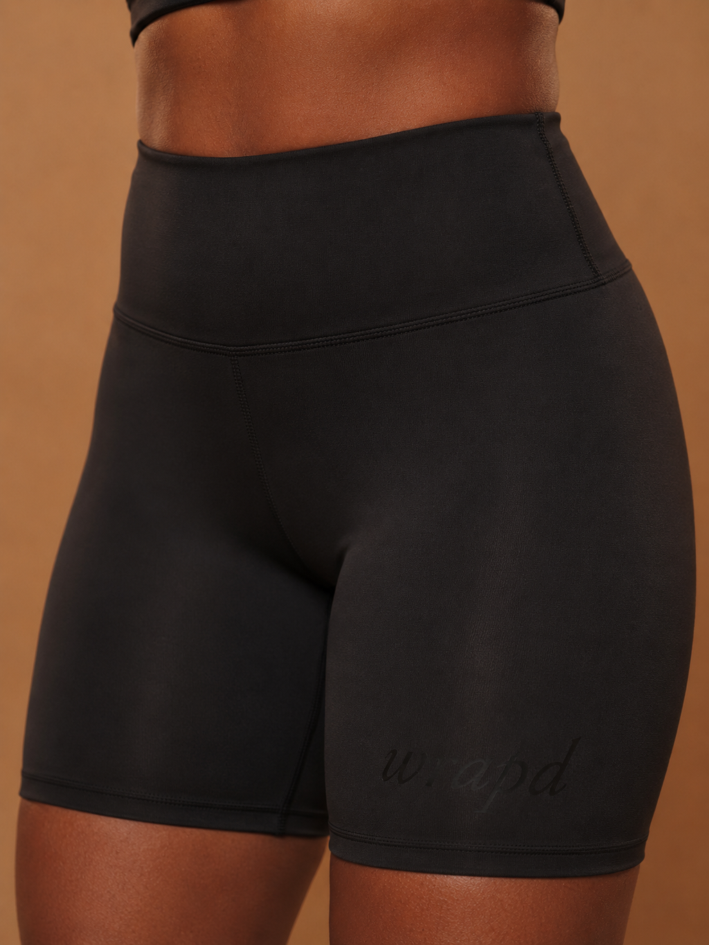 wrapd high-waisted biker short in black, front view on model